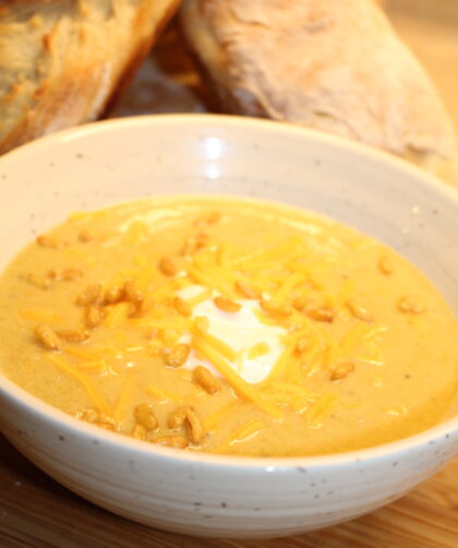 Broccoli Cheddar Soup with crackle nuts and baguettes behind