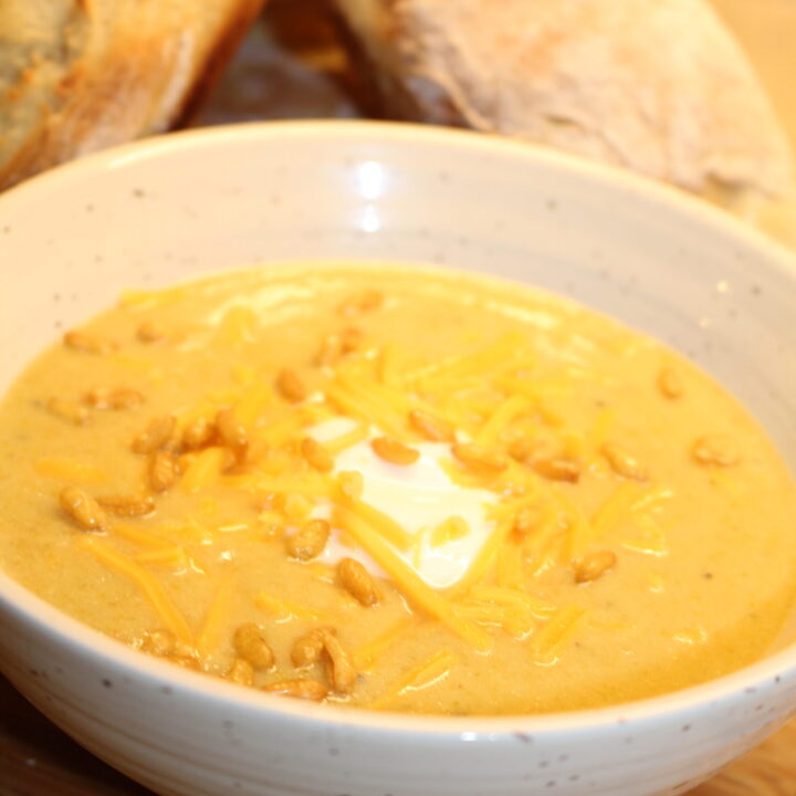 Broccoli Cheddar Soup with crackle nuts and baguettes behind