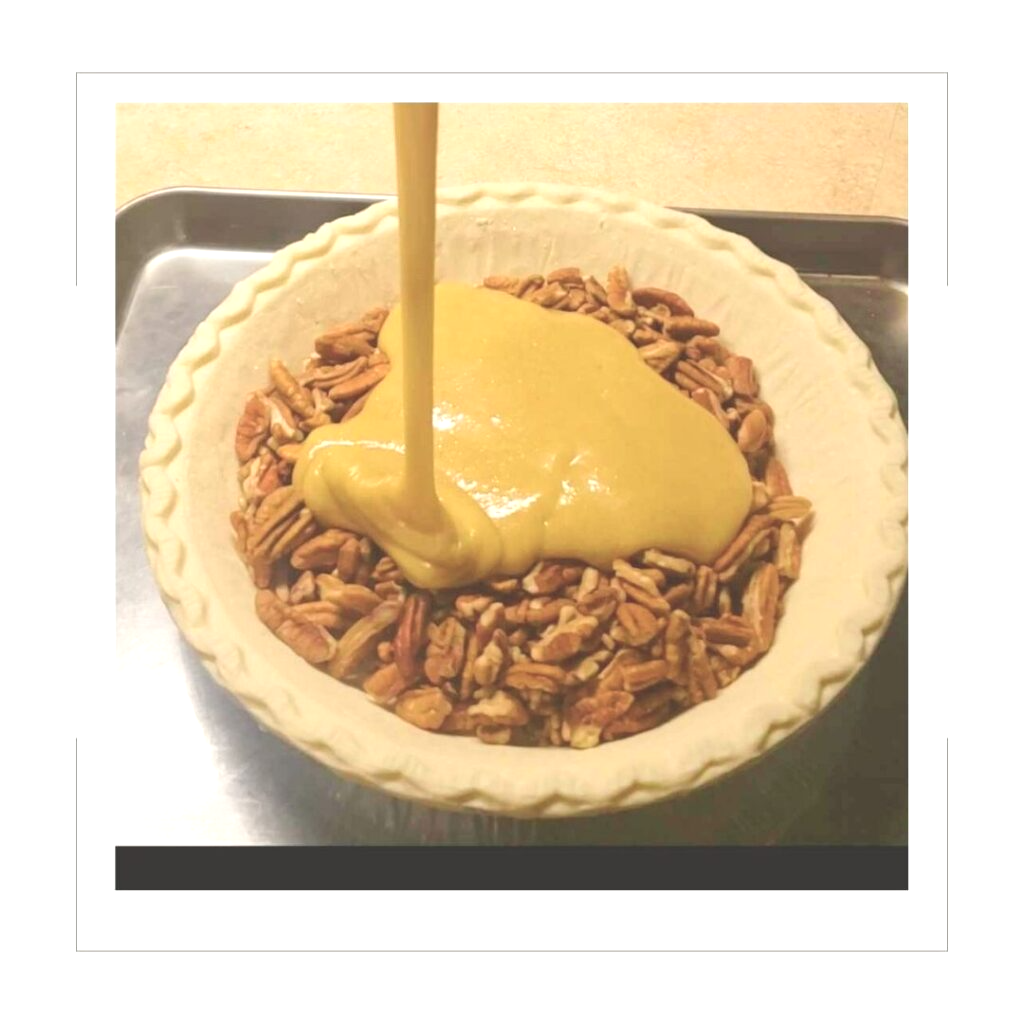 Pecan Pie filling being poured over pecans in a pie shell