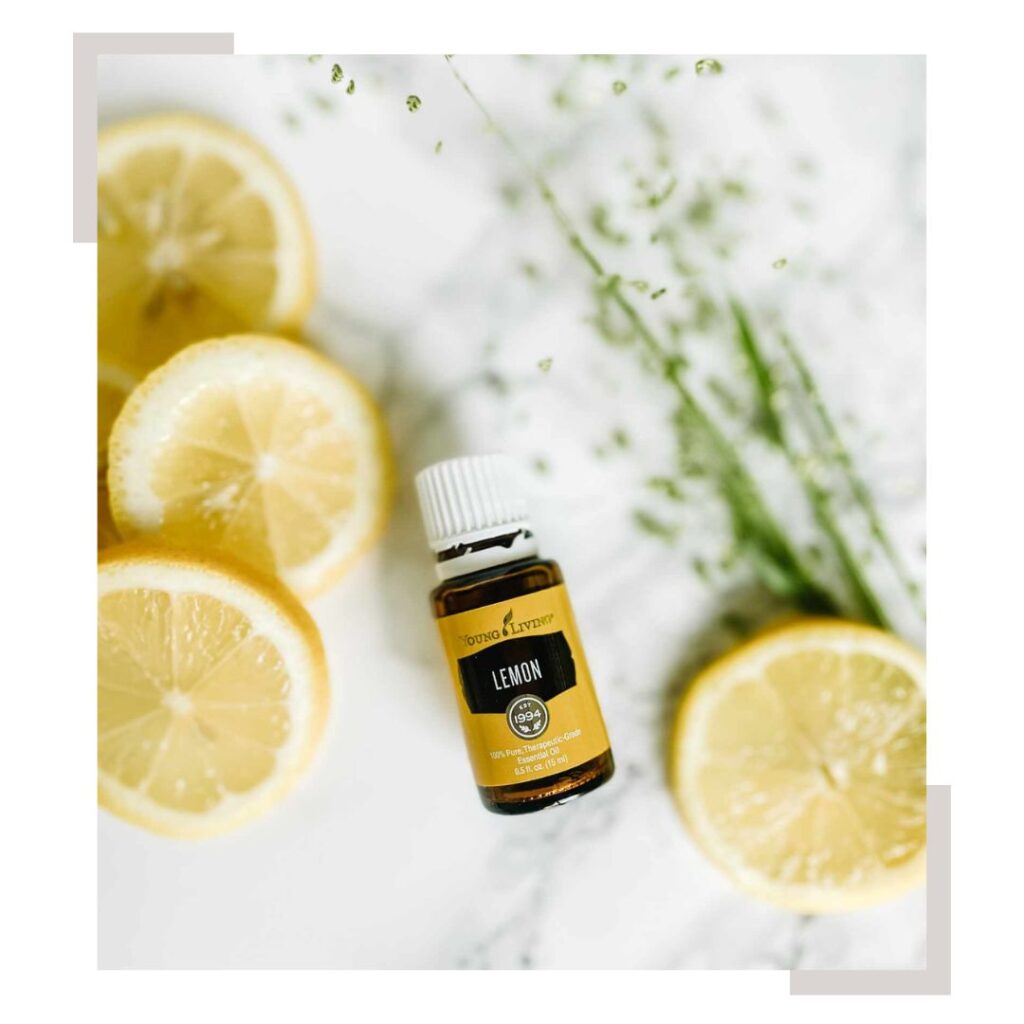 Lemon Essential Oil with lemon slices and greenery on a counter