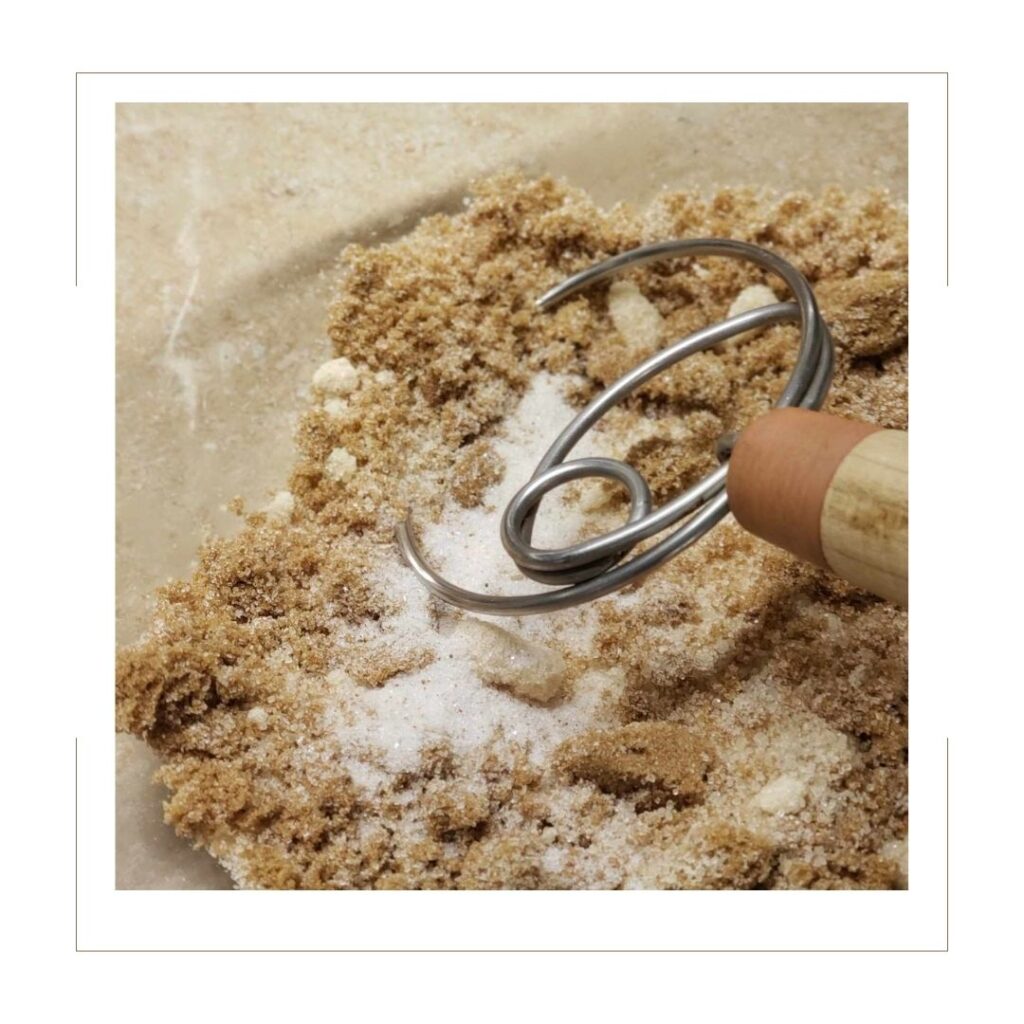 White sugar, brown sugar and sale with dough hook in a glass bowl