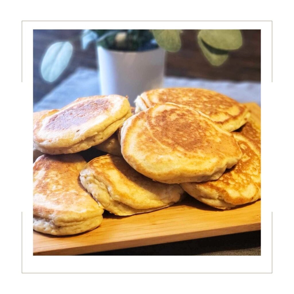 Pancake board with cooked pancakes and plant on a wooden table