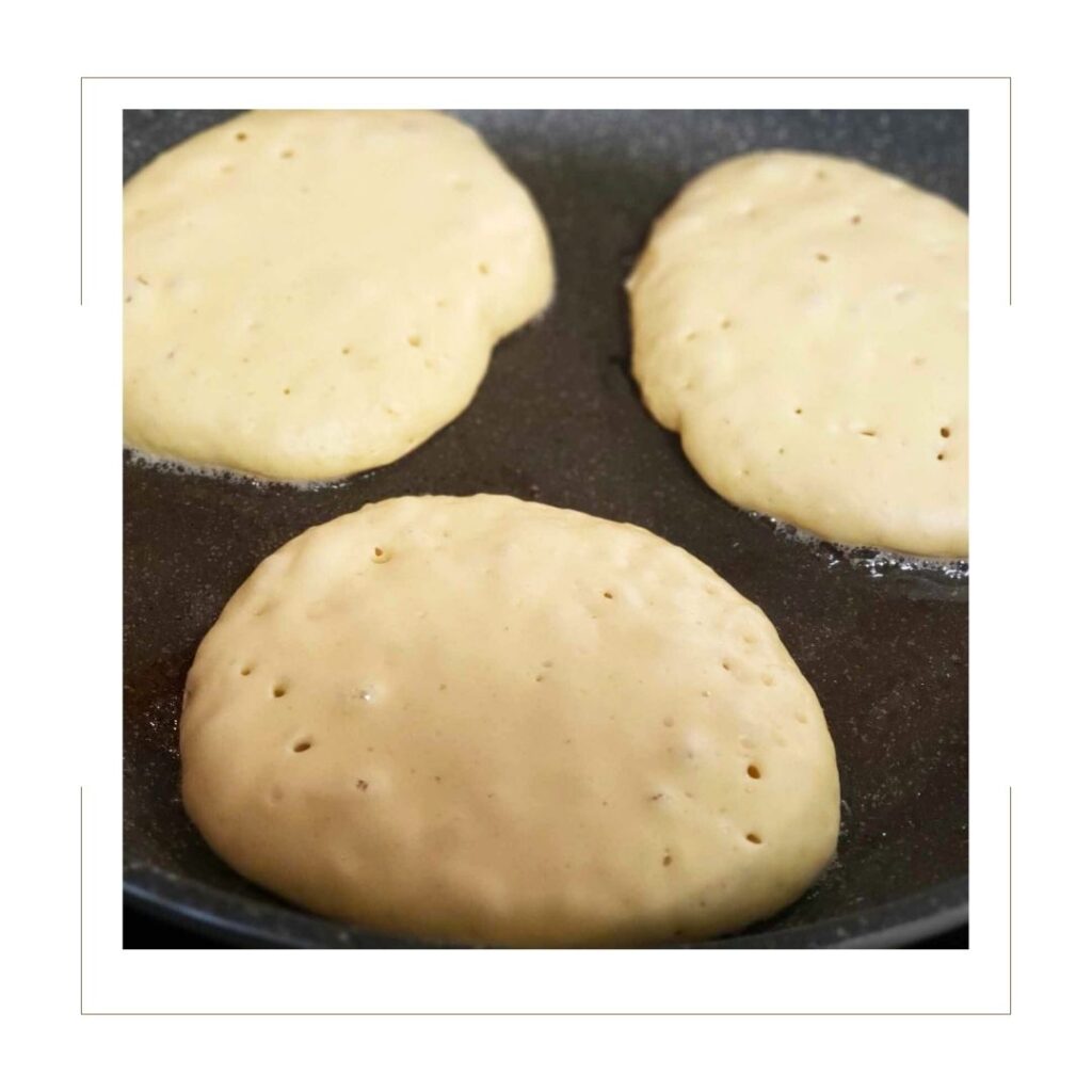 3 Uncooked Pancakes with bubbles starting to form in a skillet