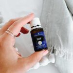 Valor Essential Oil held in hand with a white cloth behind.