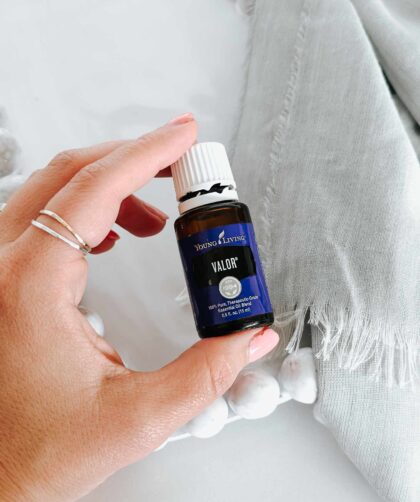 Valor Essential Oil held in hand with a white cloth behind.