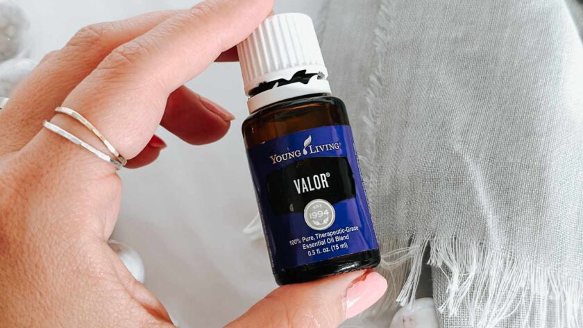 Valor Essential Oil held in hand with a white cloth behind.