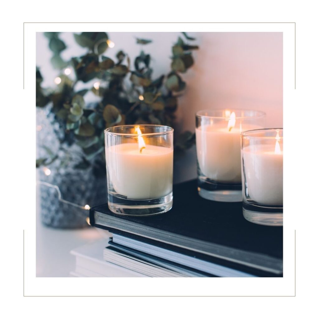 Three candles on a shelf with a plant in the background