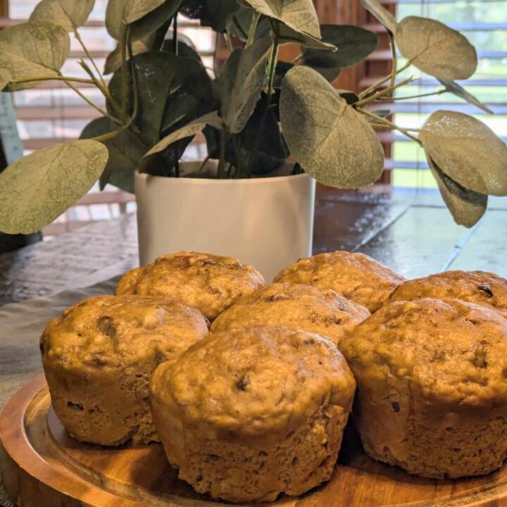 Banana Nut Muffins on table with plant in background.