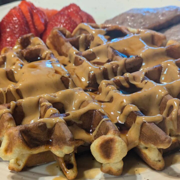 Waffle with peanut butter and syrup with strawberries and sausage