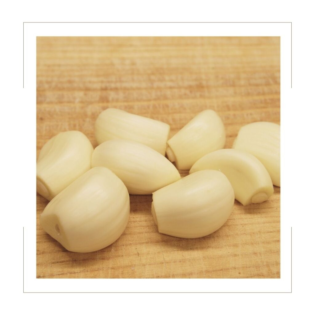raw garlic cloves on a wooden board