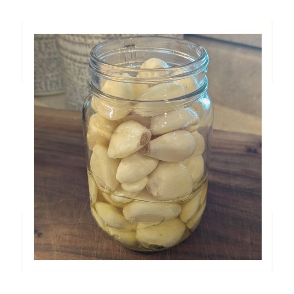 garlic and honey in a mason jar on a cutting board