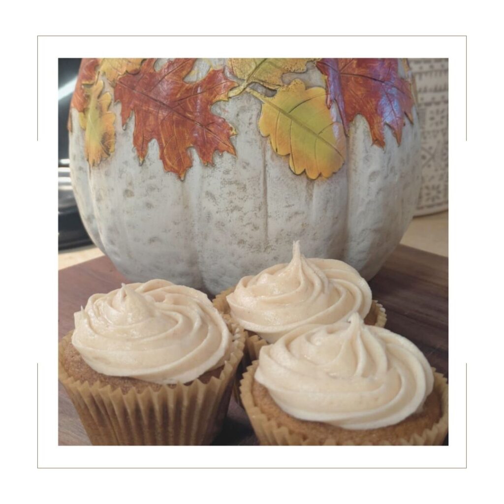 Three Pumpkin Spice Cupcakes with Cream Cheese Icing with a decorative pumpkin