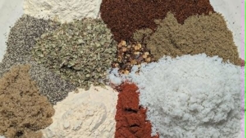 Overhead flat-lay of individual taco seasoning spices arranged on a white plate