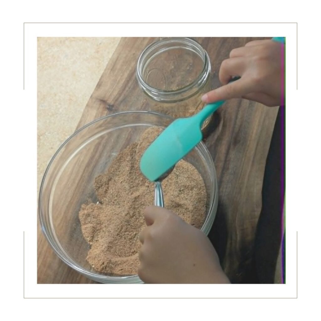 Hands mixing homemade taco seasoning in a glass bowl with a blue spatula